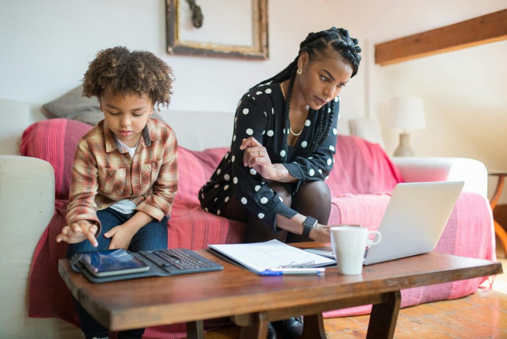 A força da mãe/professora /pós graduanda na universidade no século XXI A woman and her son using technology in a cozy living room setting.