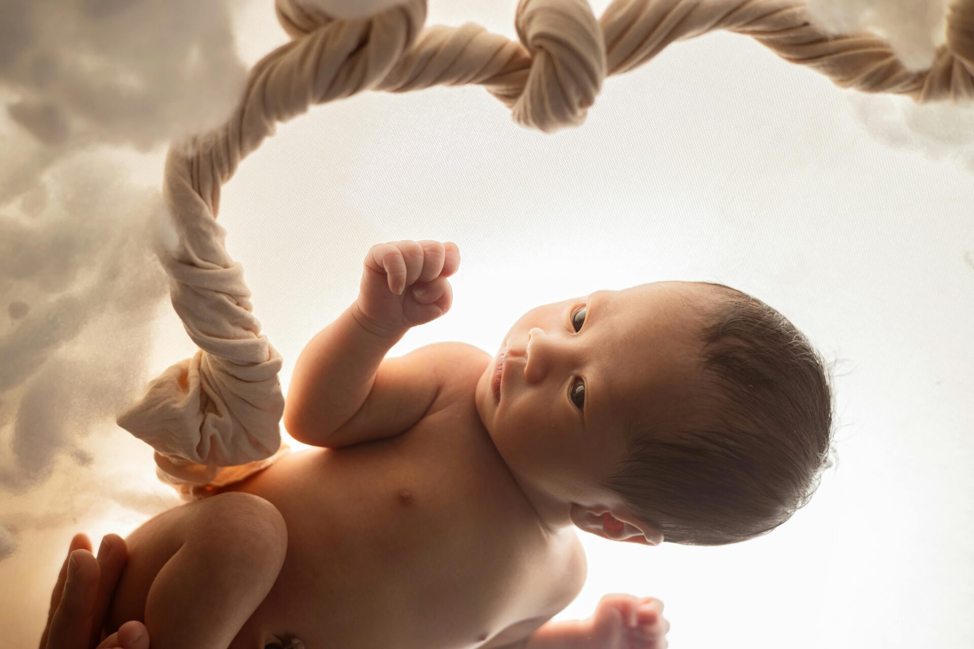 Newborn baby peacefully posed in a soft, dreamy studio setting, creating a warm and tender scene.