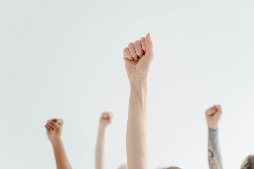 Hands raised in a gesture of strength and solidarity against a white background.