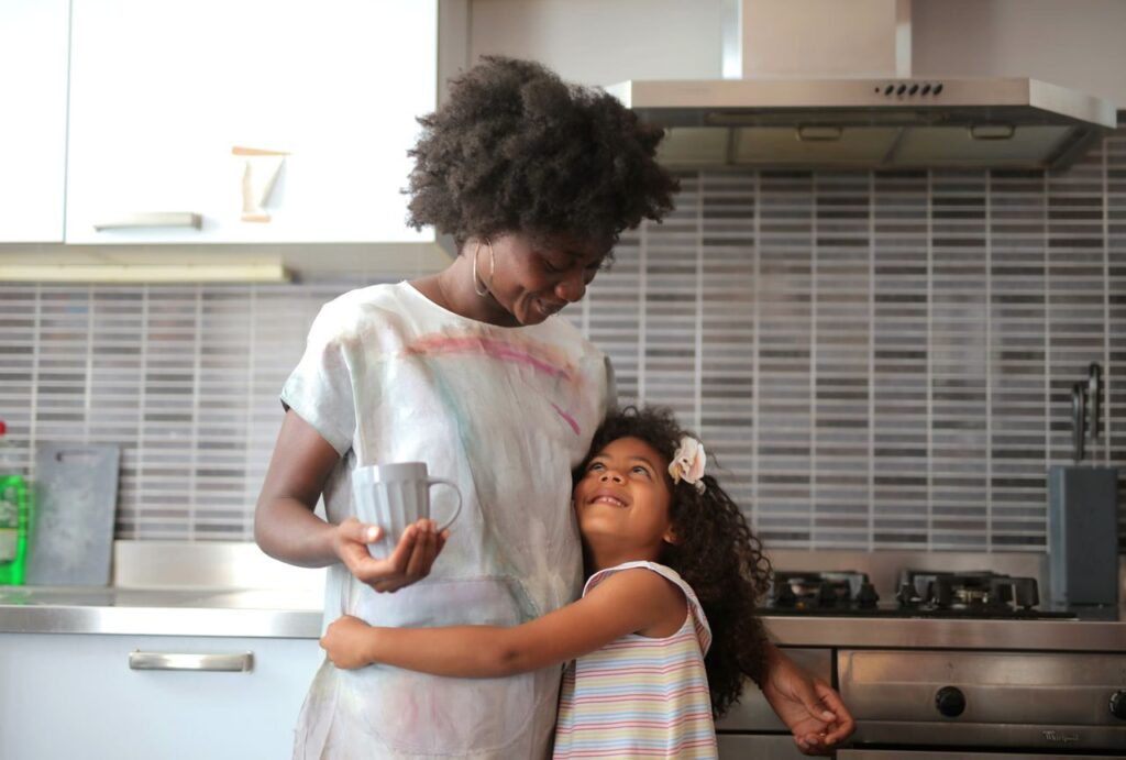 A joyful moment between mother and daughter in a modern kitchen setting.