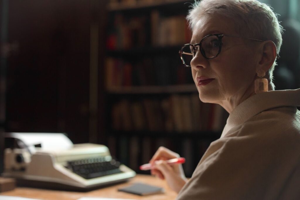 pexels-photo-7967595-7967595 Elderly woman with glasses writing in an office with a vintage typewriter.