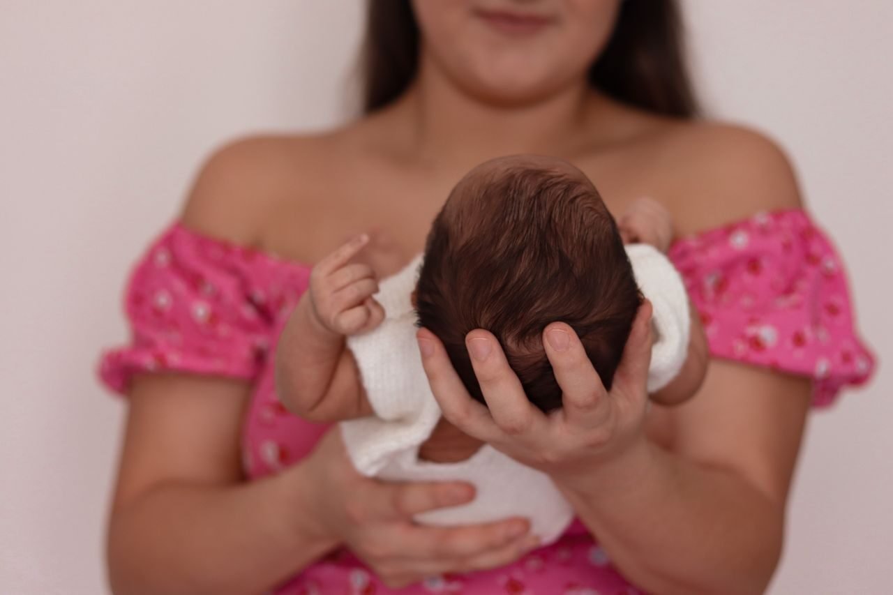 A mother gently cradles her newborn, symbolizing love and care.