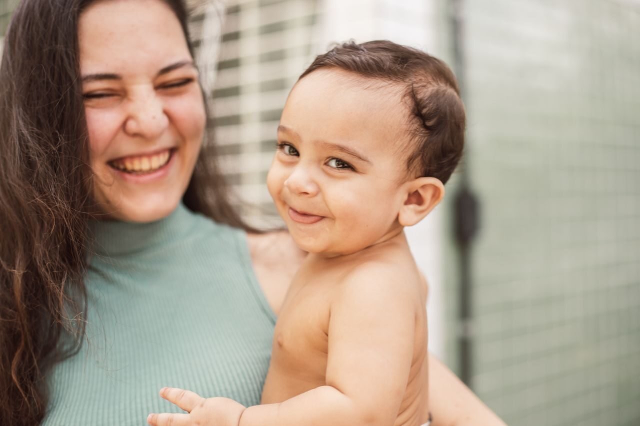 A heartwarming image of a mother and baby sharing a joyful, affectionate moment indoors.
