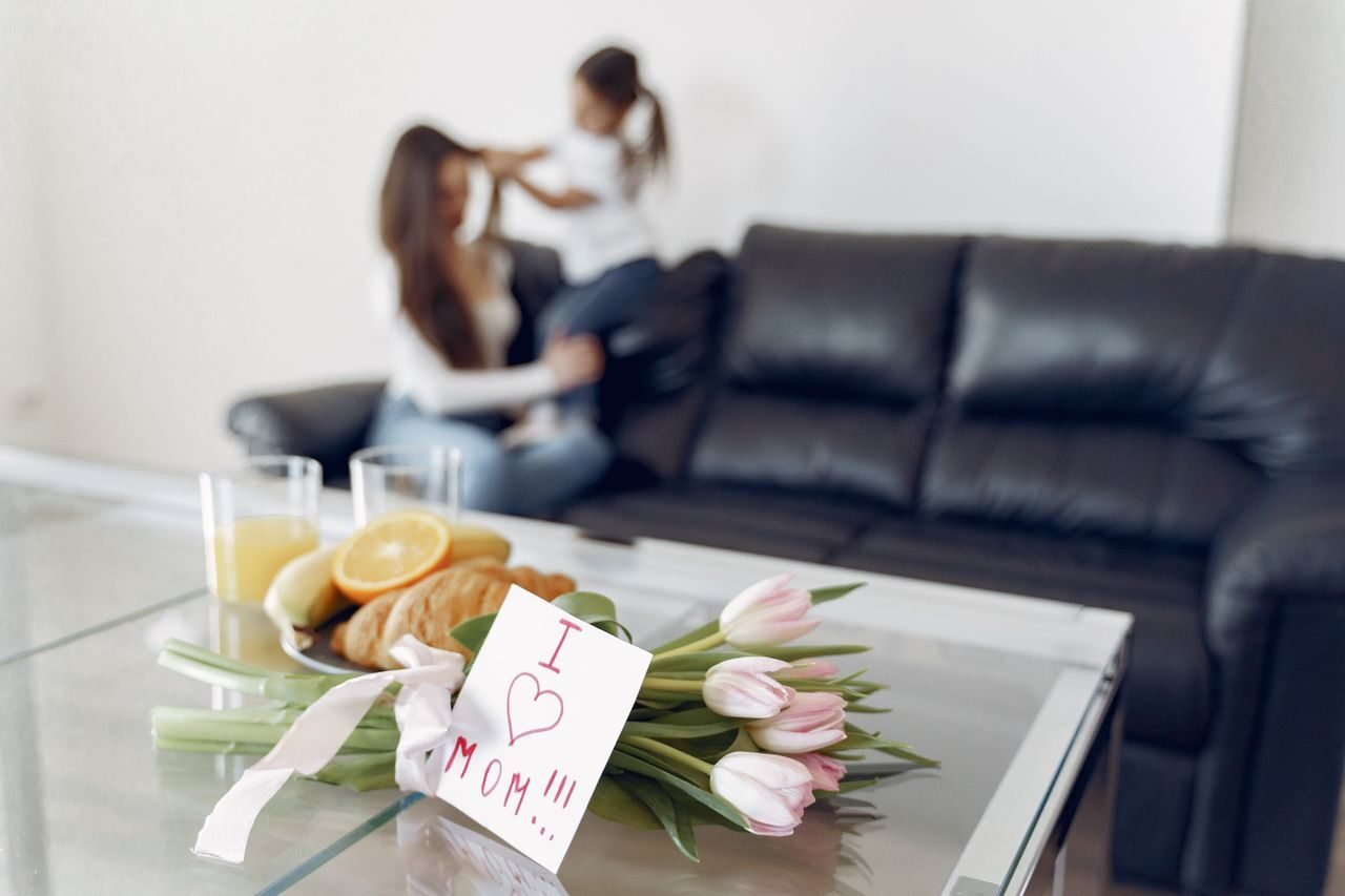 Tulips and a heartfelt note on a table with a mother and child in the background.