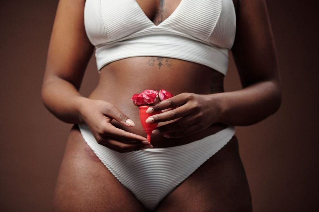Close-up of woman holding menstrual cup with flowers, promoting feminine health.