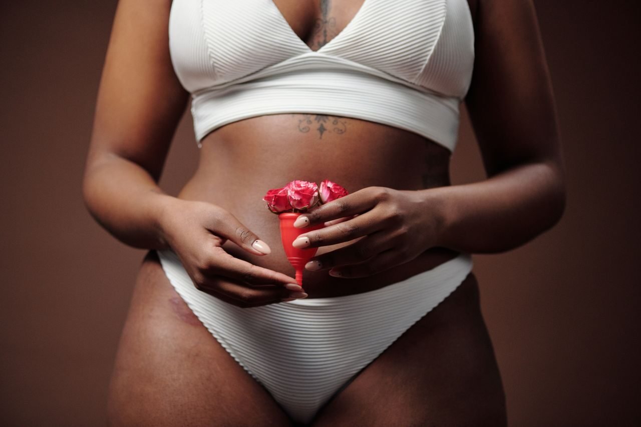 Close-up of woman holding menstrual cup with flowers, promoting feminine health.