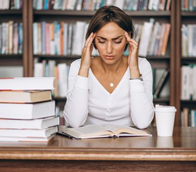 Student woman studying at the library and drinking coffee